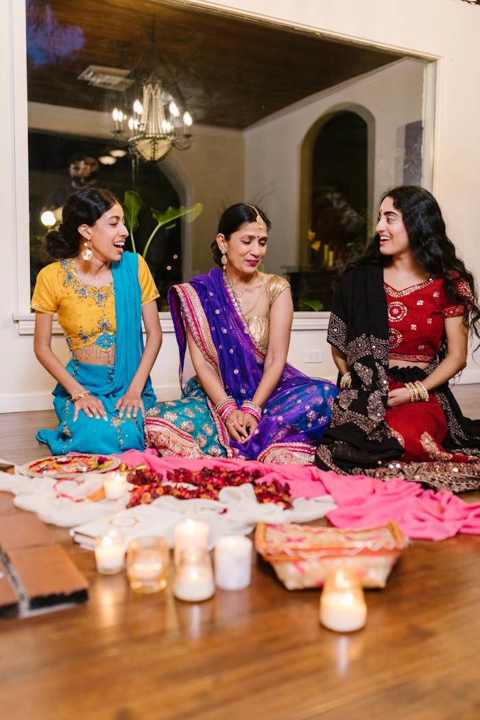 Home Three women in colorful saris enjoying a traditional Indian celebration indoors.